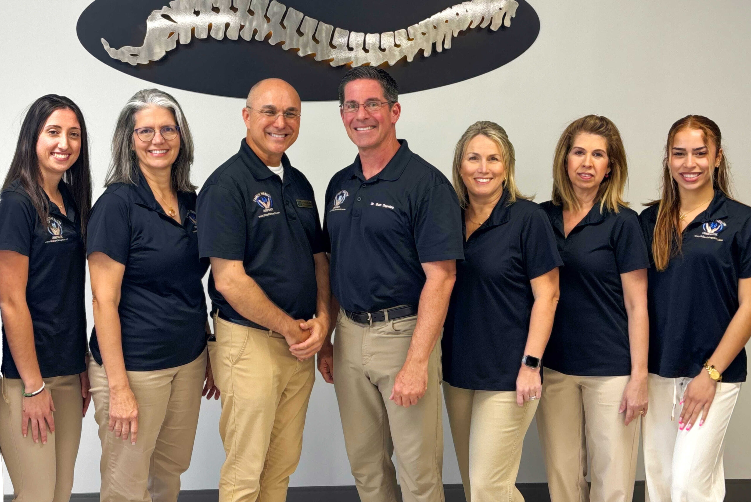 The Family Health Chiropractic Center team in Tampa, beneath the practice's spine sculpture